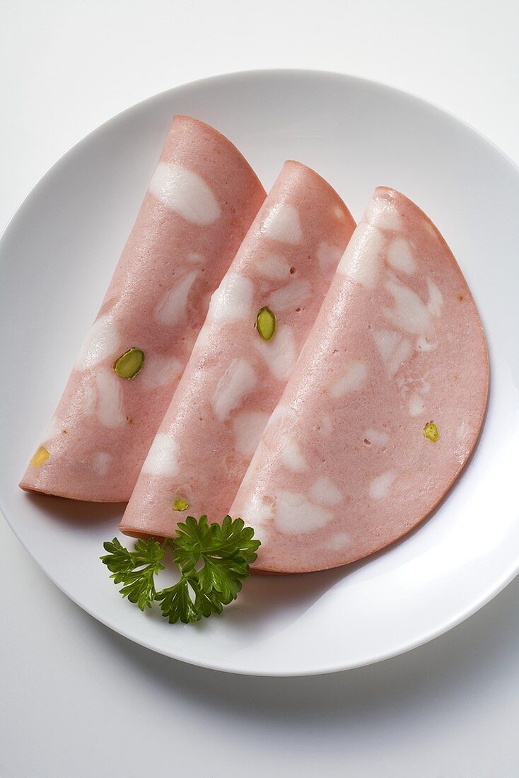 Three slices of mortadella on plate