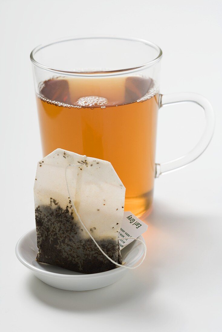 Earl Grey tea in glass cup, tea bag in foreground