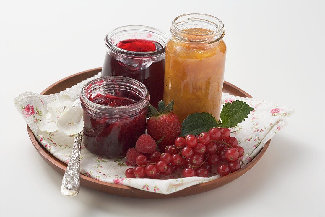 Jars of jam and fresh berries on tray