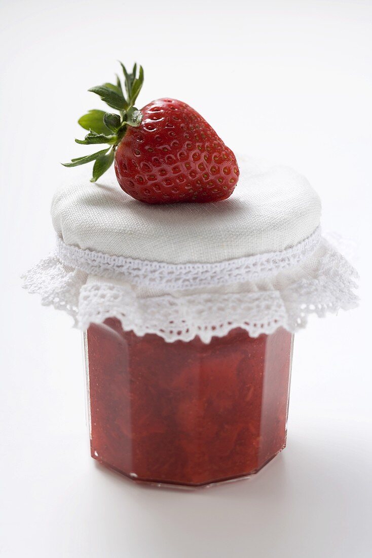 Jar of strawberry jam with a fresh strawberry