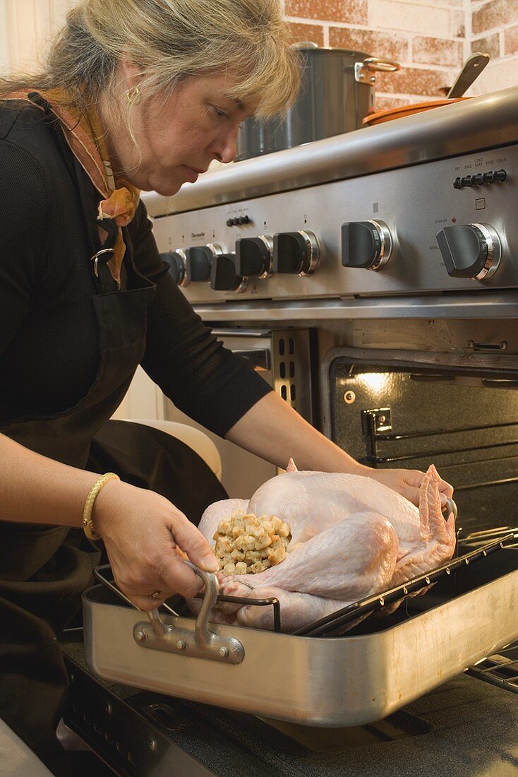 Woman putting stuffed turkey into the oven