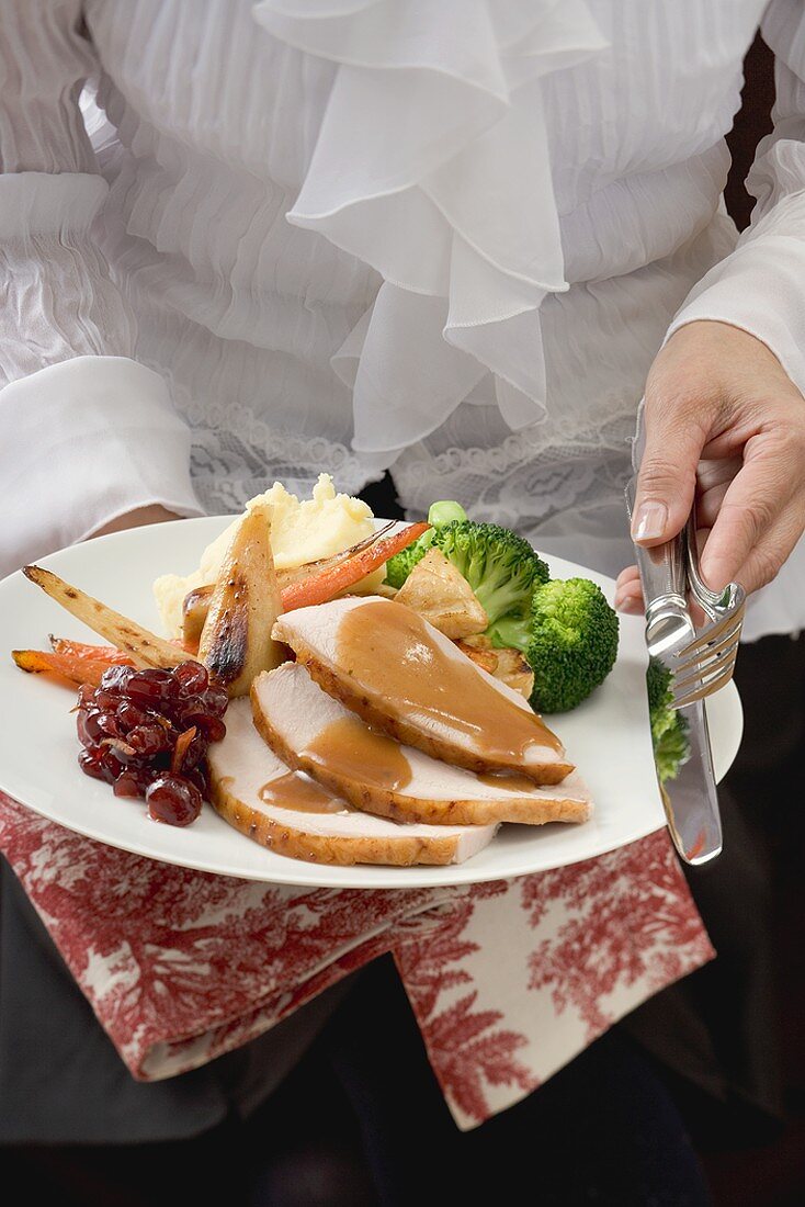 Woman serving turkey breast & accompaniments, Thanksgiving (USA)