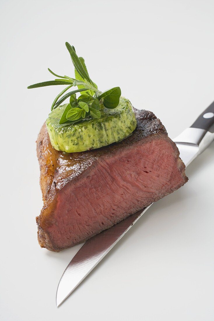 Beef steak with herb butter on knife (showing cut edge)