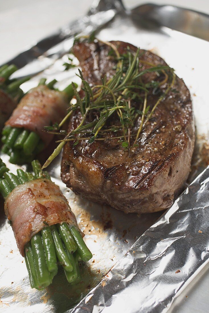 Beef steak with bacon-wrapped beans on aluminium foil