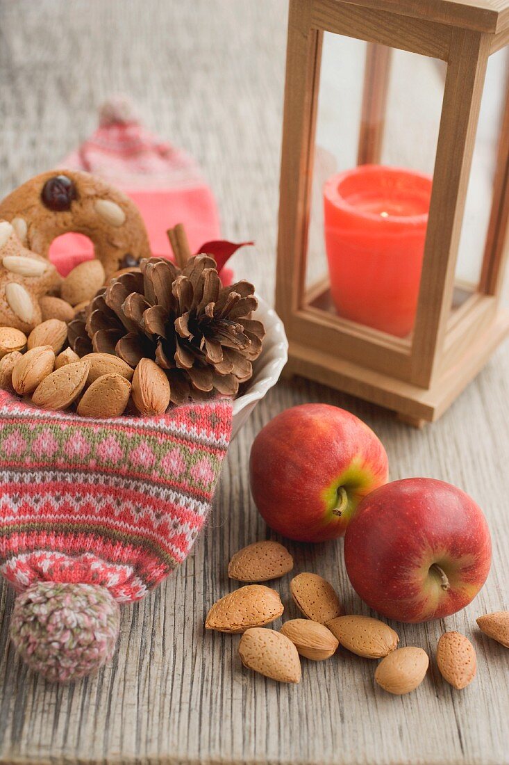 Rustikale Weihnachtsdeko mit roten Äpfeln, Nüssen und Laterne