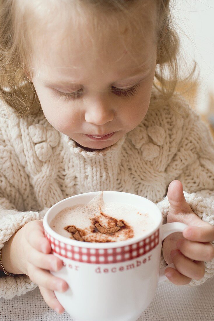 Kleines Mädchen trinkt Kakao aus grosser Tasse