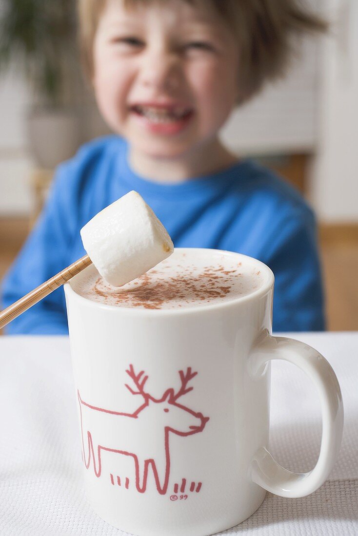 Tasse Kakao mit Marshmallow, kleiner Junge im Hintergrund