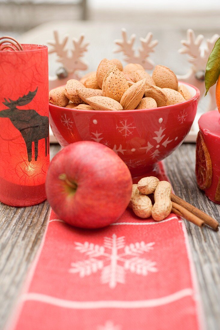 Weihnachtsdeko mit Nüssen, Apfel, Zimt und Kerze
