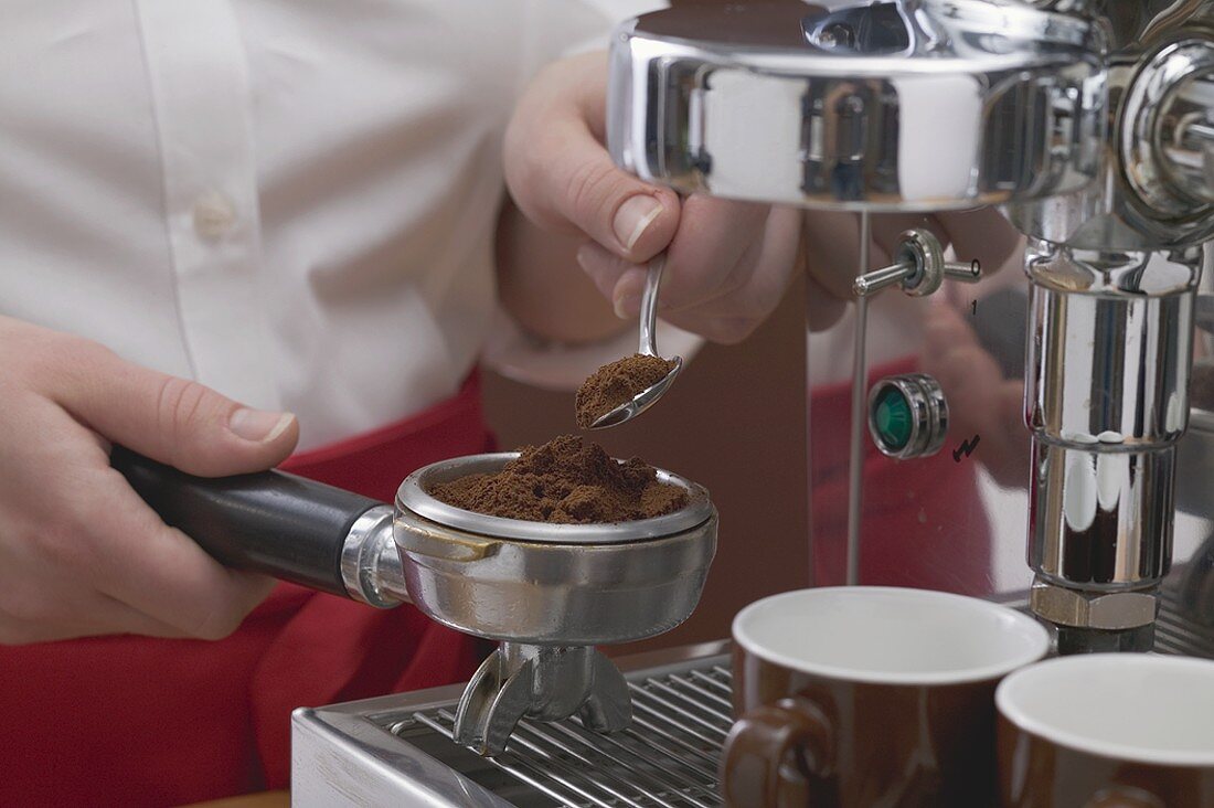 Woman filling filter holder with ground espresso coffee