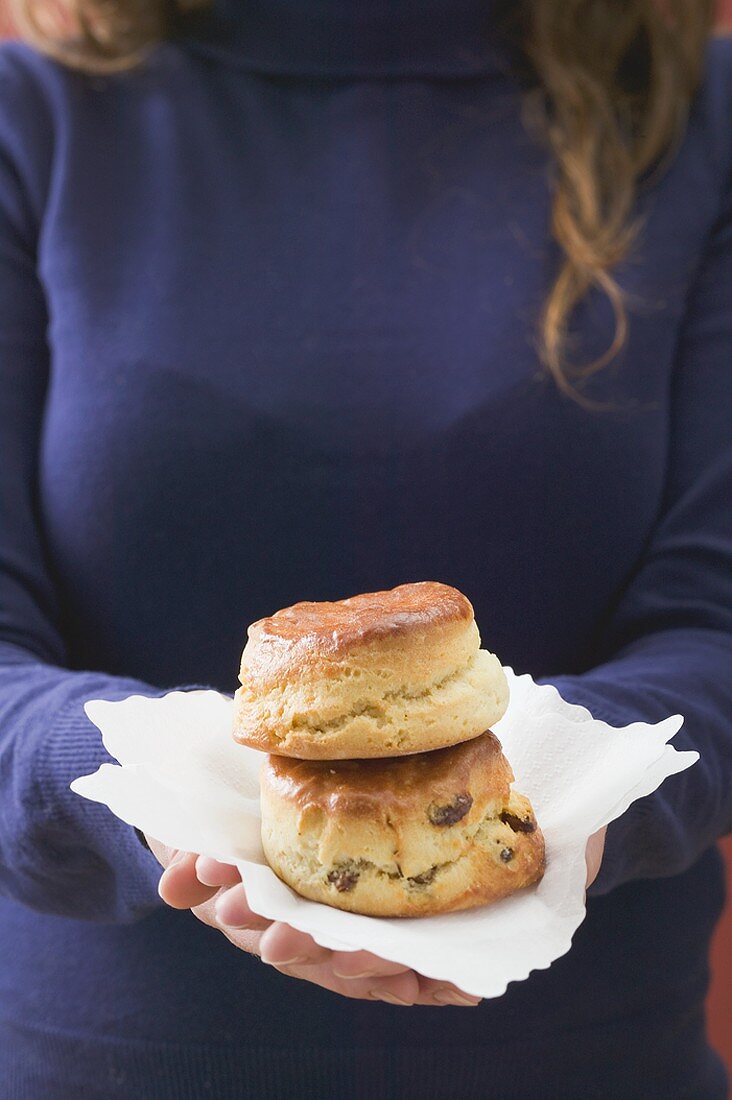 Frau hält zwei Scones auf Papierserviette