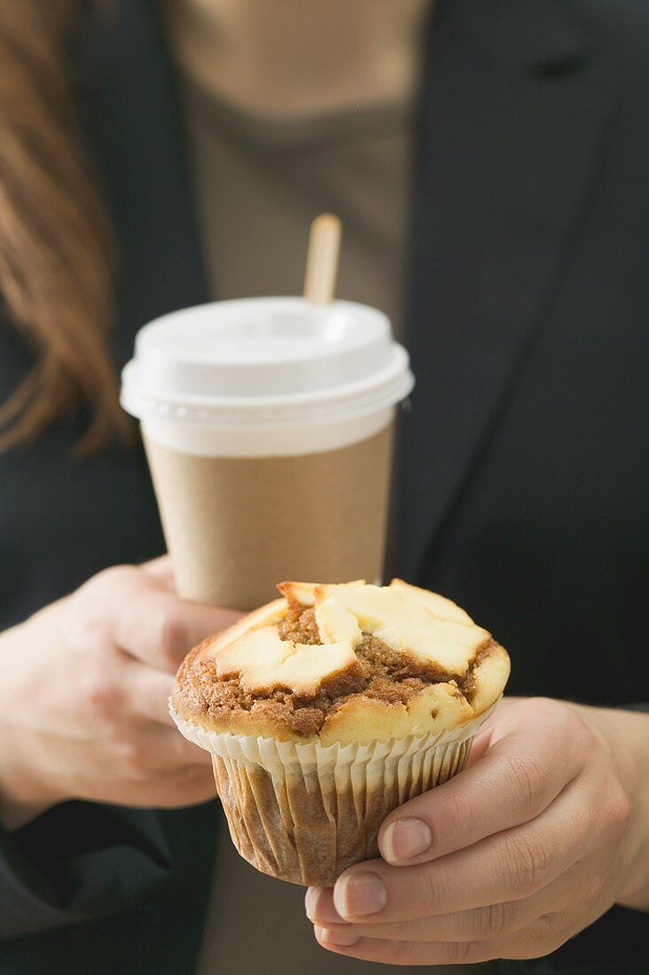 Woman holding muffin and cup of coffee