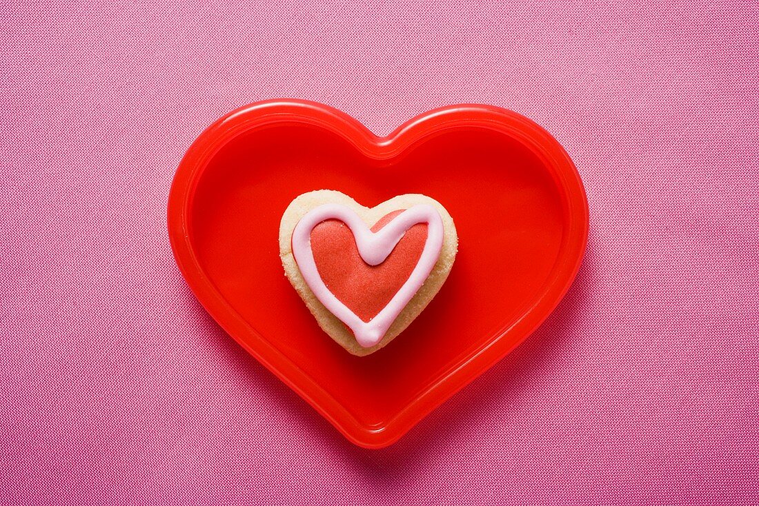 Heart-shaped iced biscuit in red dish