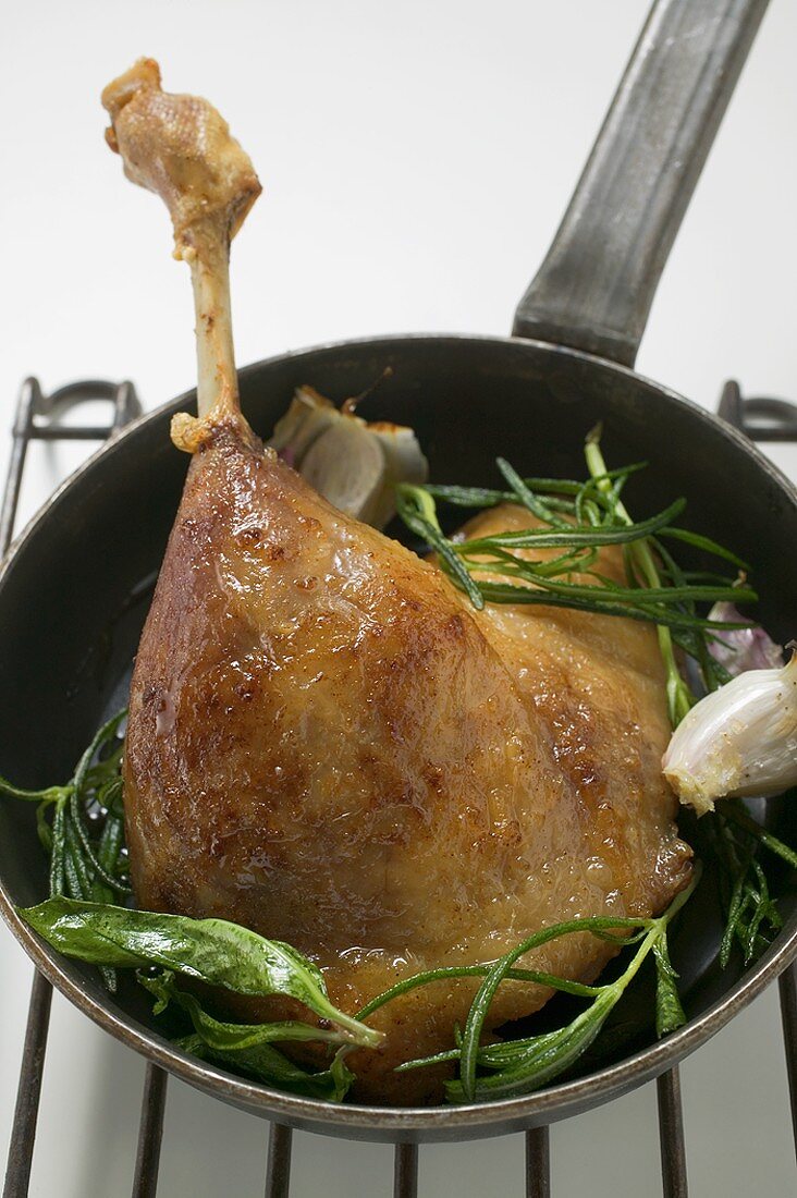 Fried goose leg with rosemary in frying pan