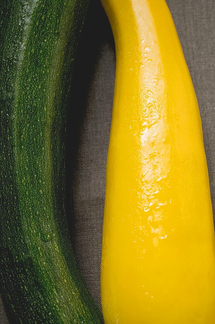Gelbe und grüne Zucchini auf braunem Stoffuntergrund