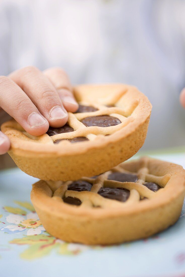 Child's hand reaching for chocolate tartlet