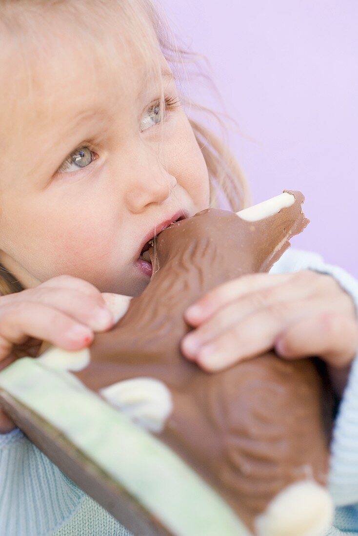 Kleines Mädchen isst Schokoladenosterhase