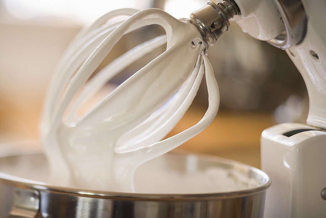 Whipped cream on balloon whisk of food mixer