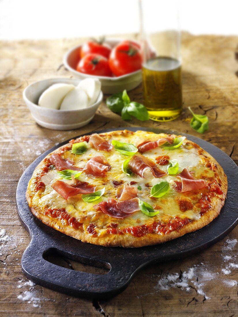 Pizza mit Tomaten, Mozzarella, Schinken und Basilikum
