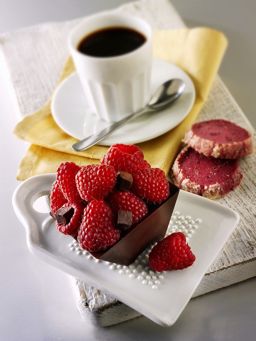 Small chocolate cake with raspberries and cup of coffee