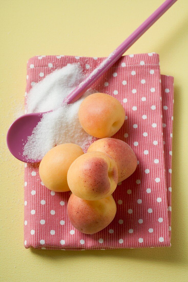 Apricots on tea towel, cooking spoon and sugar