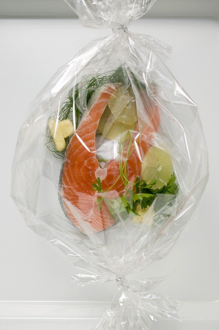 Lachs mit Kräutern und Zitronenscheiben in einer Plastikfolie