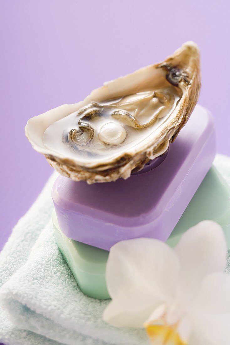 Oyster with pearl and two bars of soap on towel, orchid