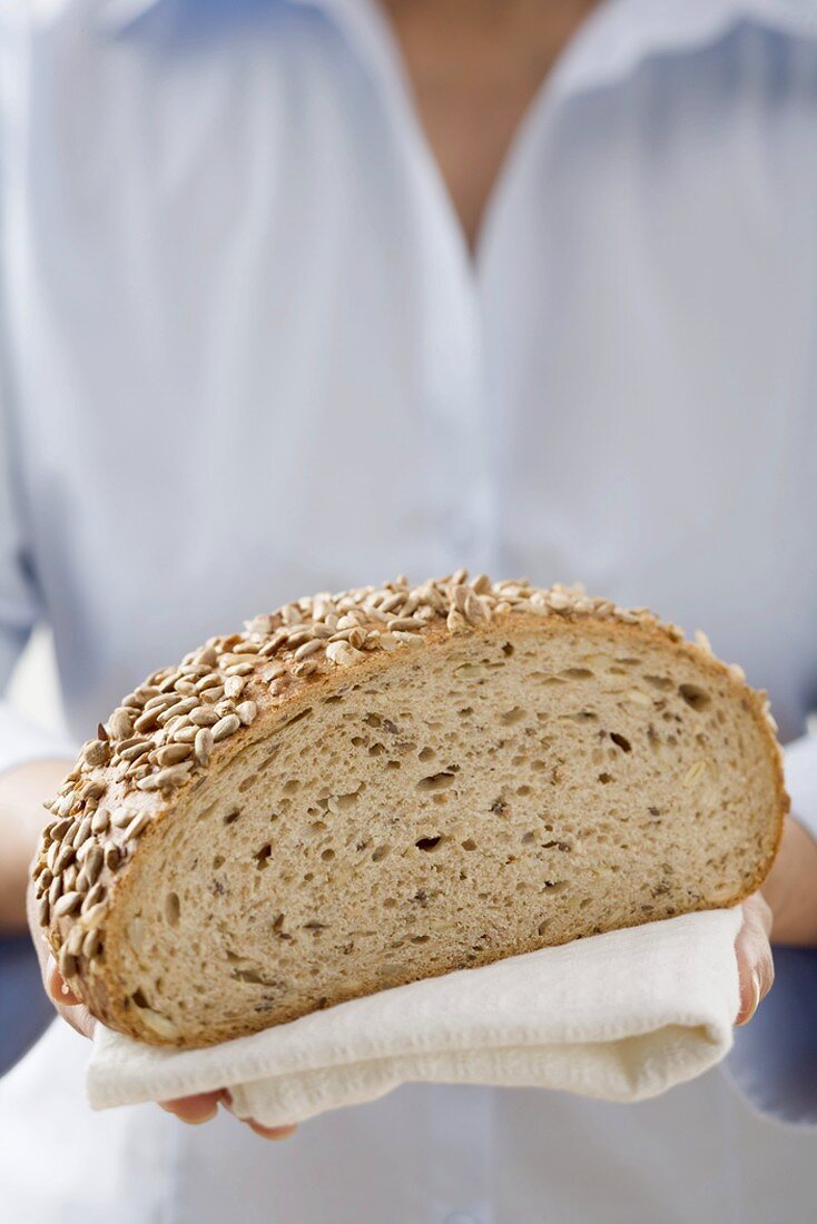 Woman holding sunflower bread (part of a loaf)