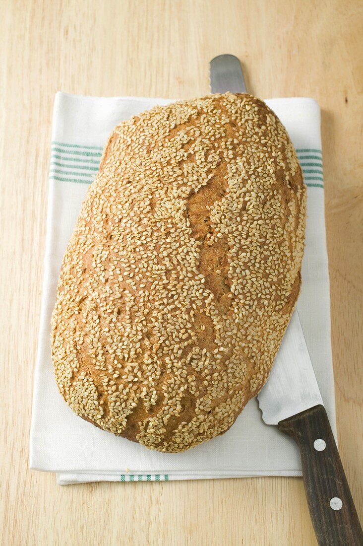 Sesambrot auf Geschirrtuch mit Brotmesser