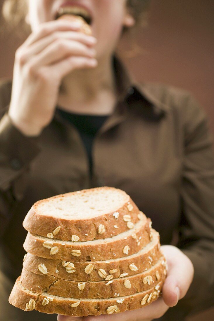 Woman holding slices of bread (with rolled oats)