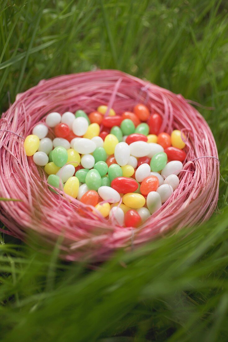 Easter nest full of coloured sugar eggs in grass