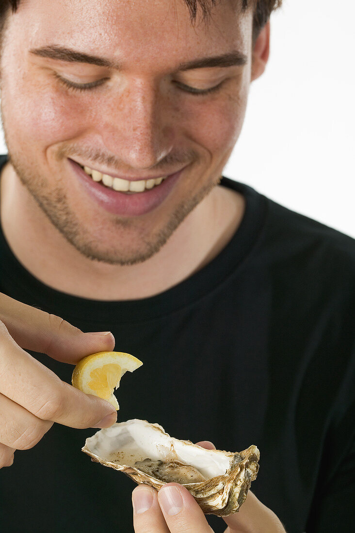 Mann träufelt Zitronensaft auf frische Auster
