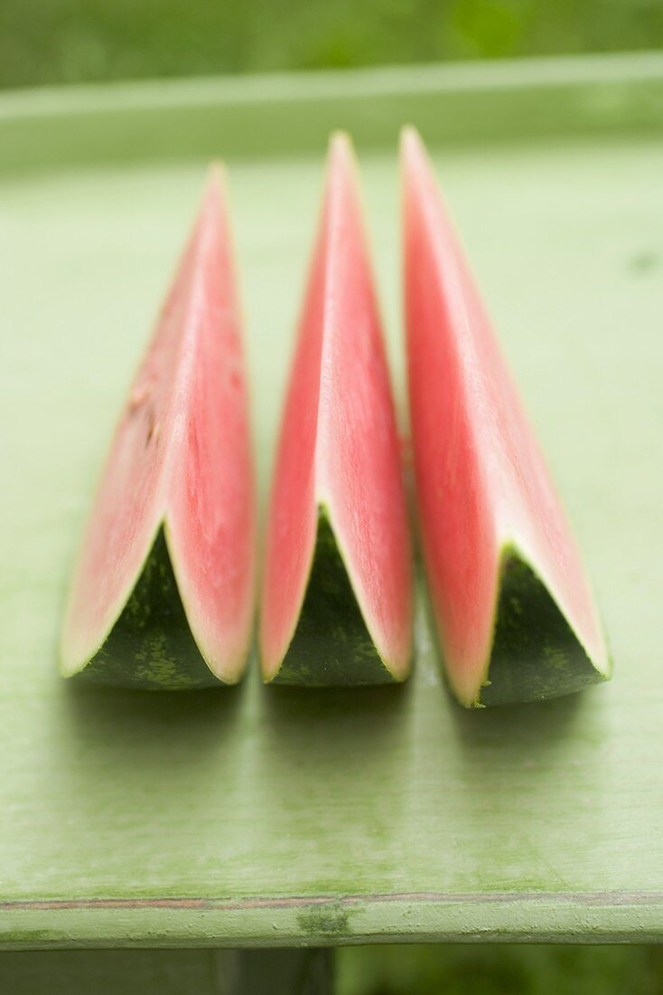 Drei Wassermelonenschnitze auf grünem Tisch