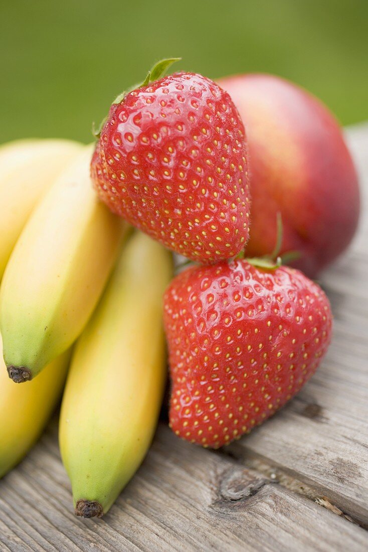 Bananas, strawberries and nectarine on wooden table