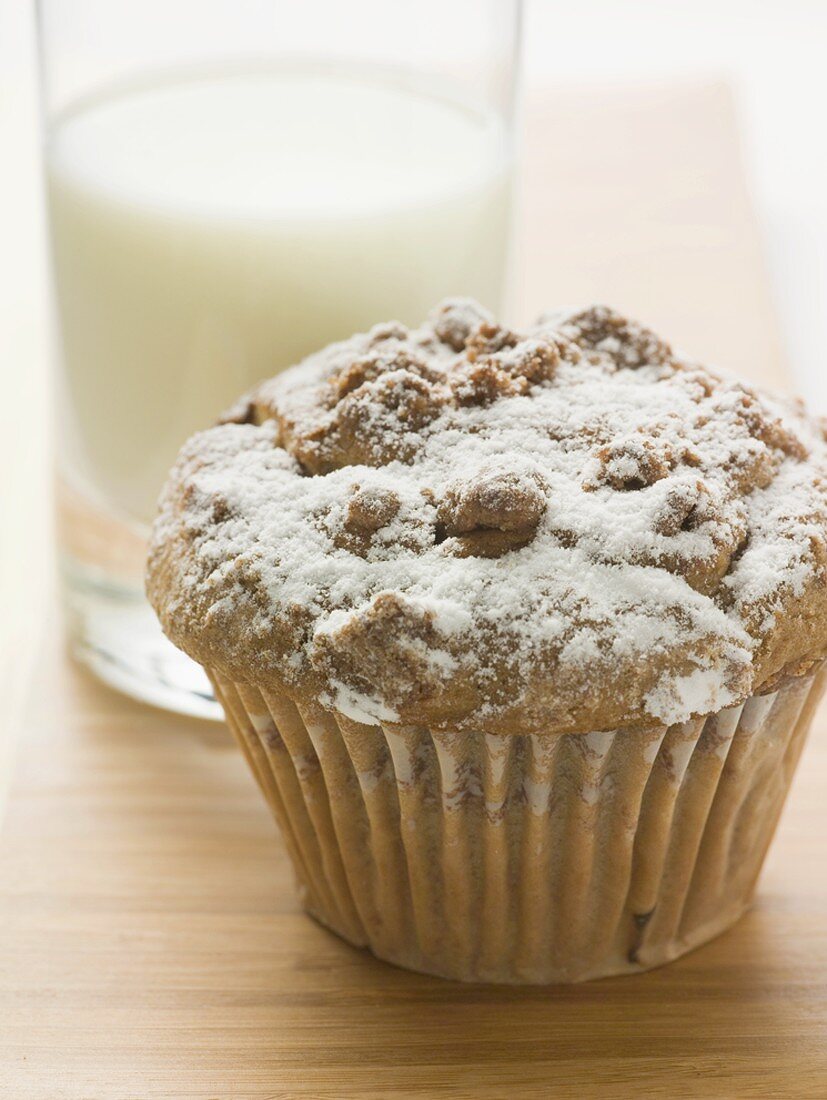 Nussmuffin mit Puderzucker vor Glas Milch