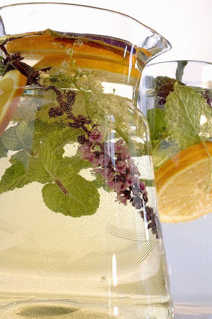 Herbal drink with slices of lemon in glass jug