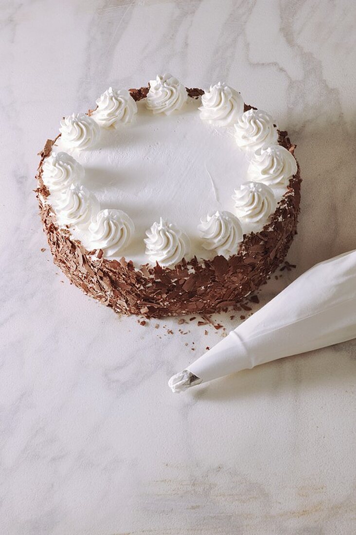 Buttercremetorte mit Schokoraspeln, daneben Spritzbeutel