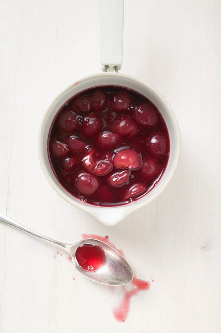 Cherry compote in pan, spoon beside it