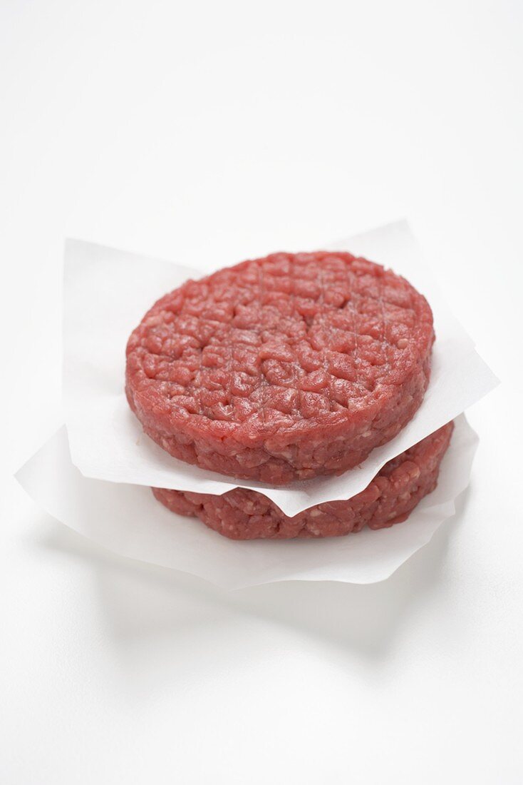 Two raw burgers on paper