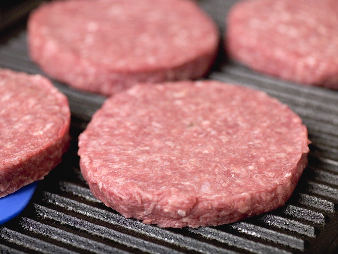 Raw burgers on electric grill