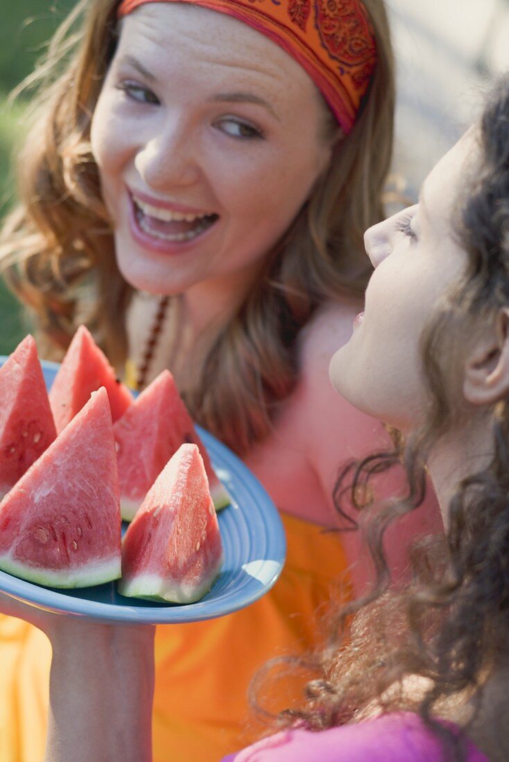 Two young women with wedges of watermelon