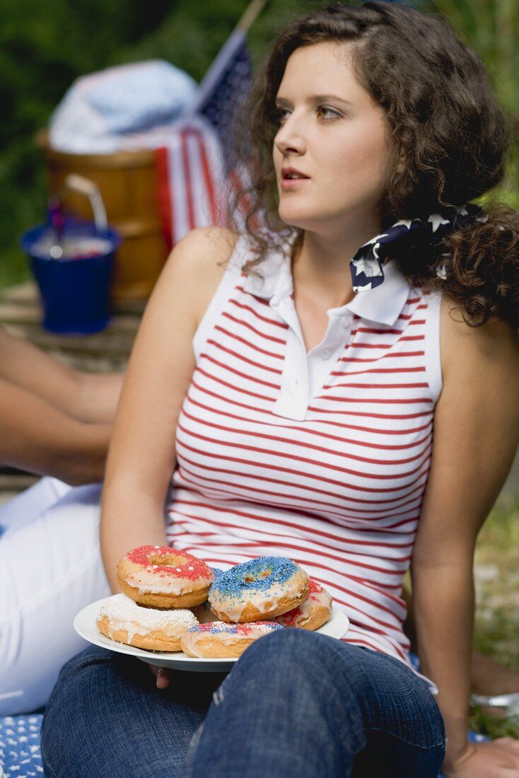 Young woman holding plate of doughnuts on the 4th of July (USA)
