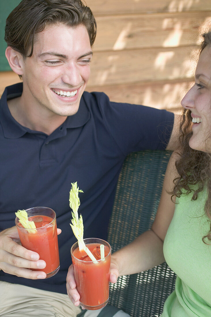 Young couple with tomato drinks out of doors