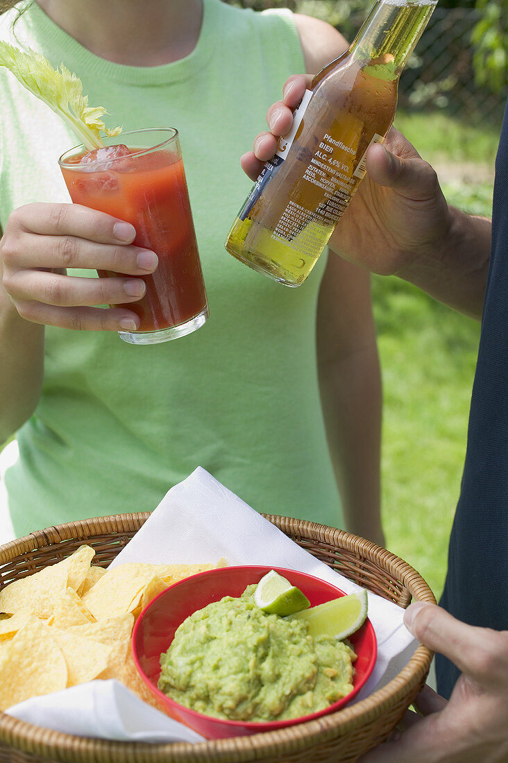 Young couple with guacamole, chips and drinks