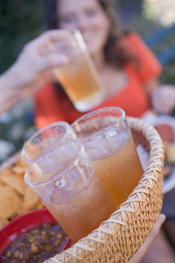 Person serving a basket of iced tea and snacks
