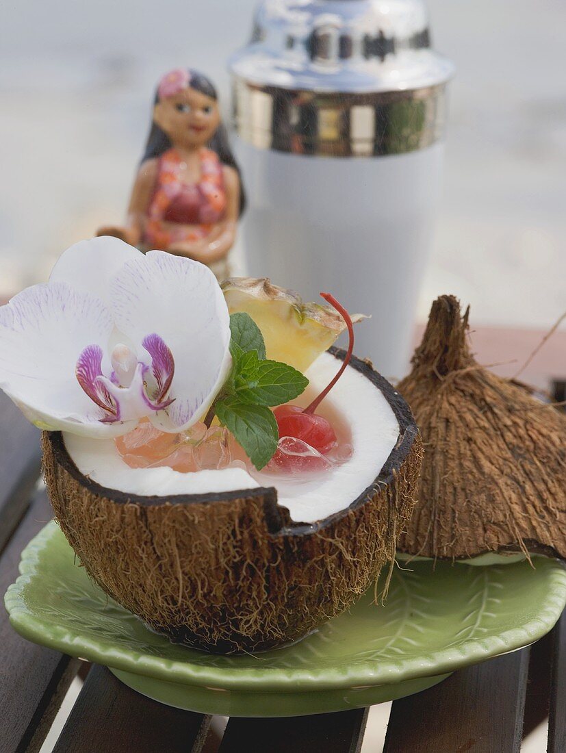 Kokosnussdrink mit Eiswürfeln, Cocktailkirsche und Orchidee