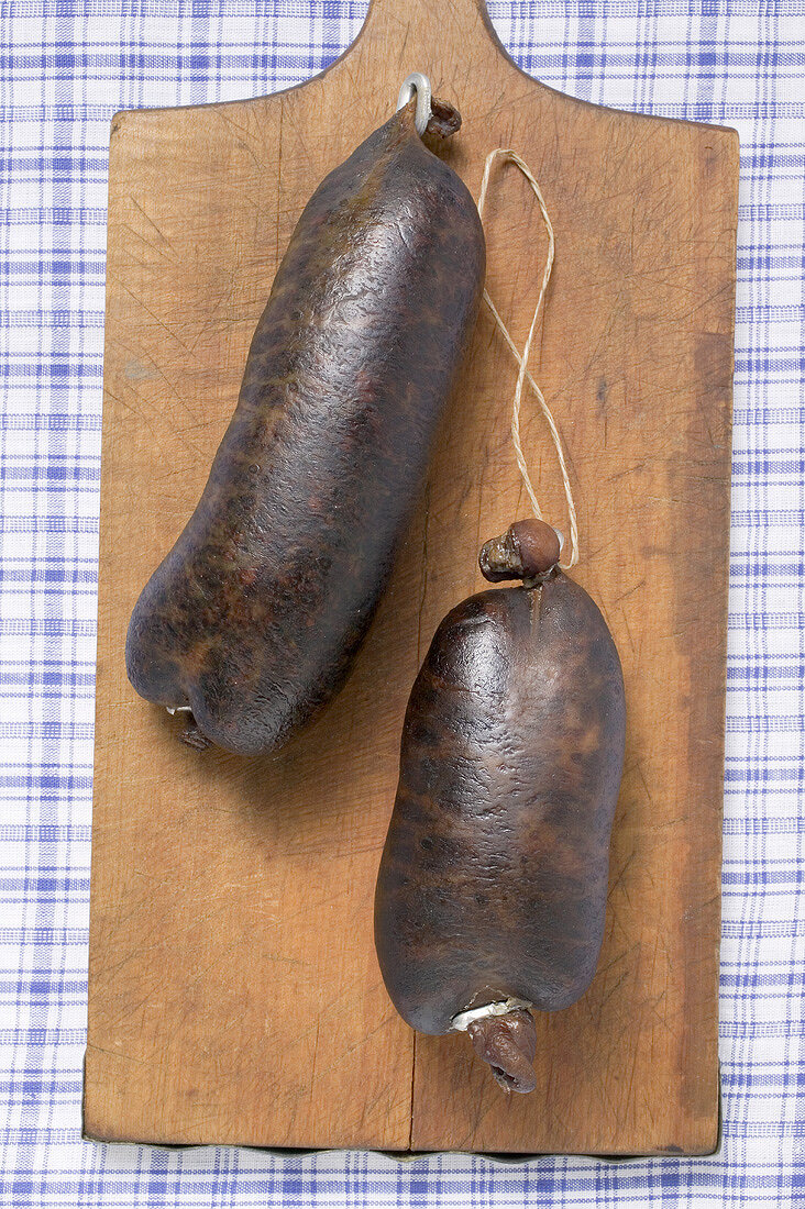 Two black puddings on chopping board (overhead view)