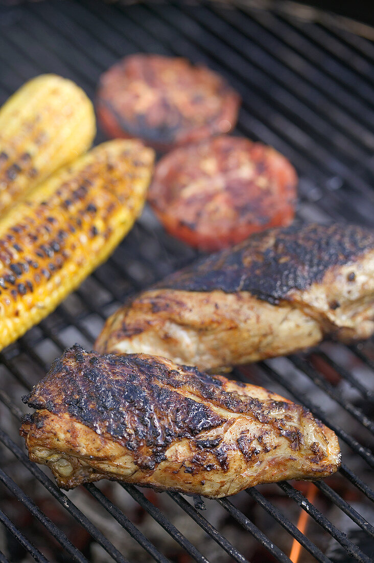 Chicken breast, tomatoes and corn on the cob on a barbecue