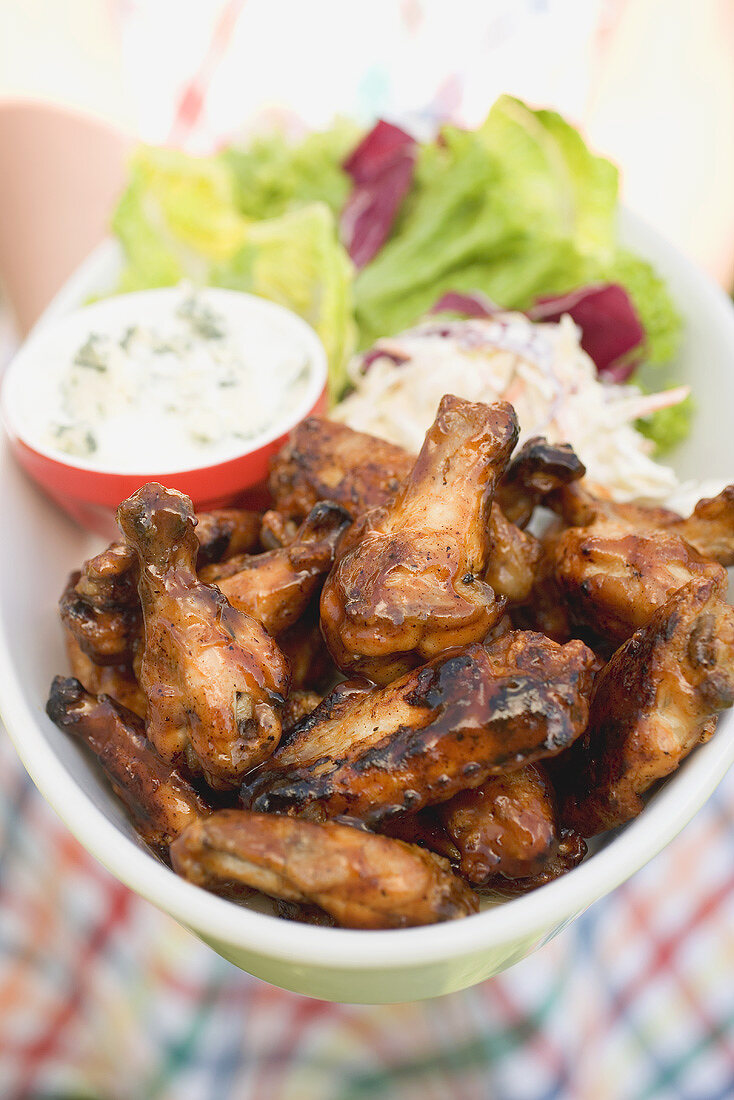 Woman holding chicken wings with blue cheese dip and salad