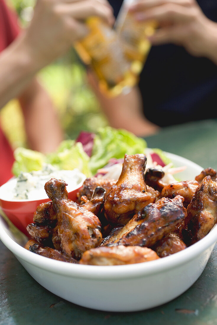 Grilled chicken wings, men with beer in background