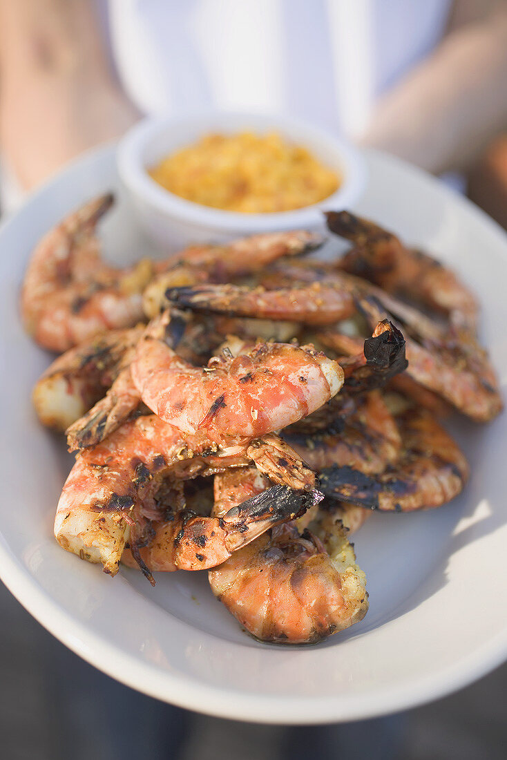 Person hält Teller mit gegrillten Shrimps